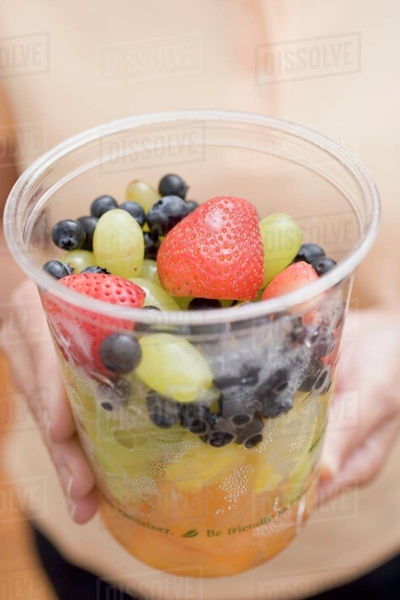 Woman holding plastic tub of fruit salad - Royalty-free Stock Photo |  Dissolve