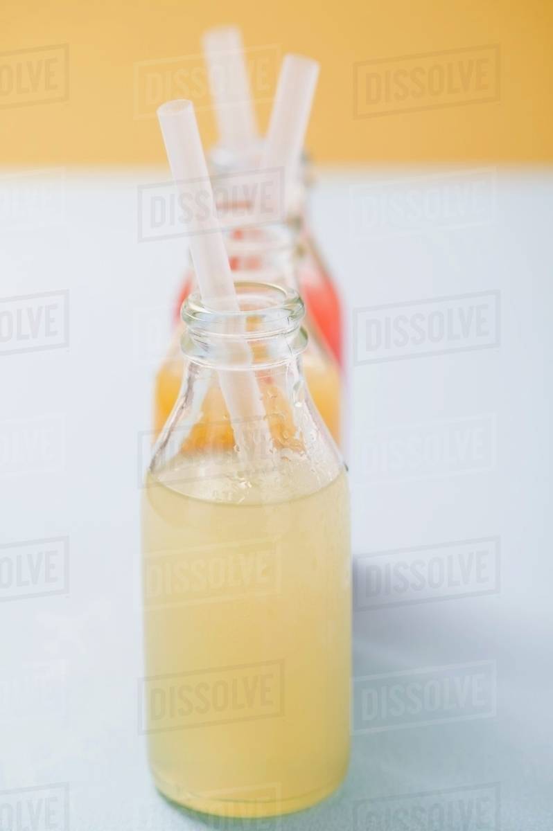 Three fruit juices in bottles with straws Stock Photo Dissolve