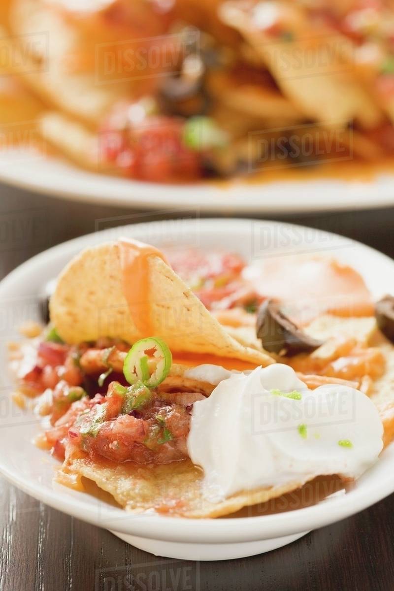 Tortilla chips with melted cheese, olives and sour cream Stock Photo