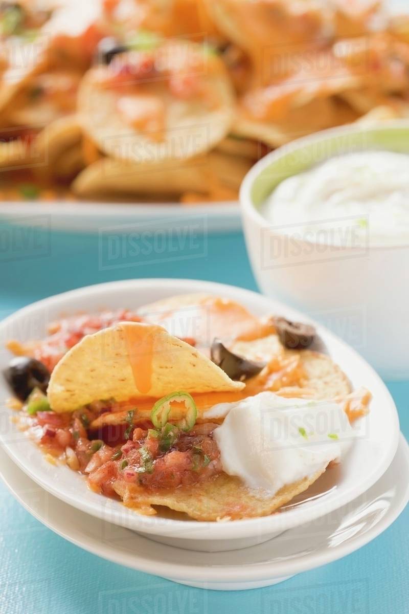 Tortilla chips with melted cheese, olives and sour cream Stock Photo
