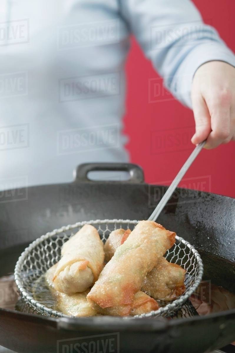 Deepfrying spring rolls in wok Stock Photo Dissolve
