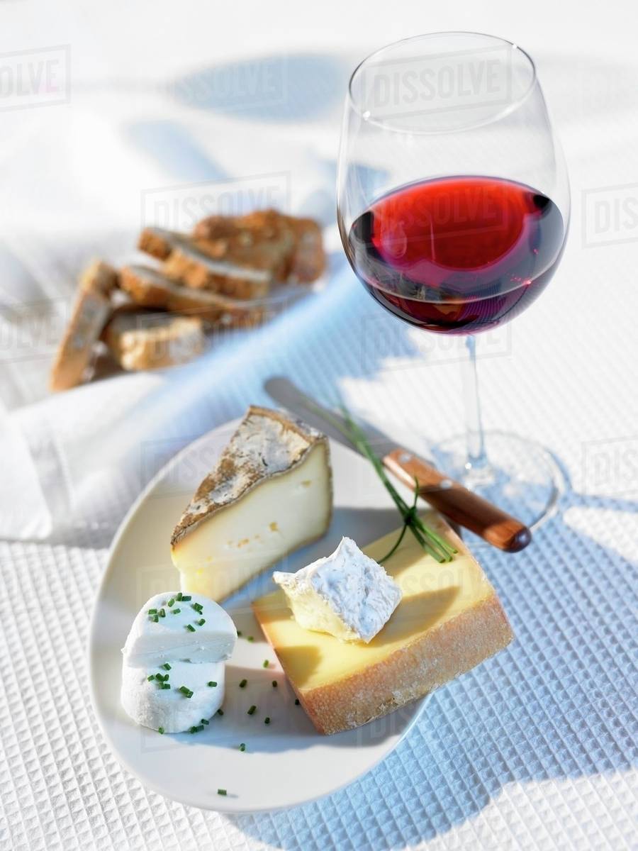 Cheese platter, glass of red wine and bread Stock Photo Dissolve
