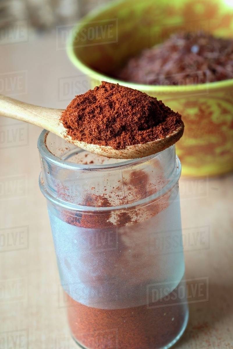 Cayenne pepper on a spoon over a jar Stock Photo Dissolve