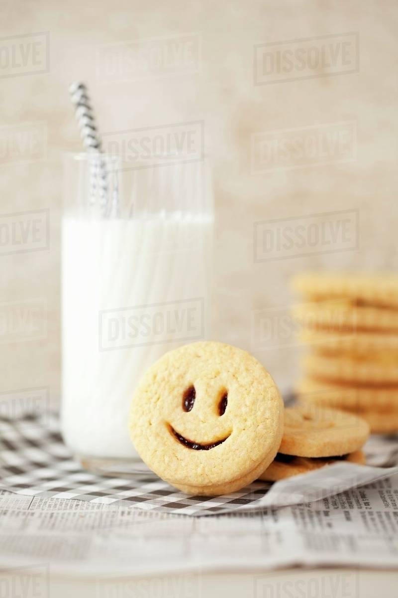Smiley jam sandwich biscuits with a glass of milk Stock Photo Dissolve