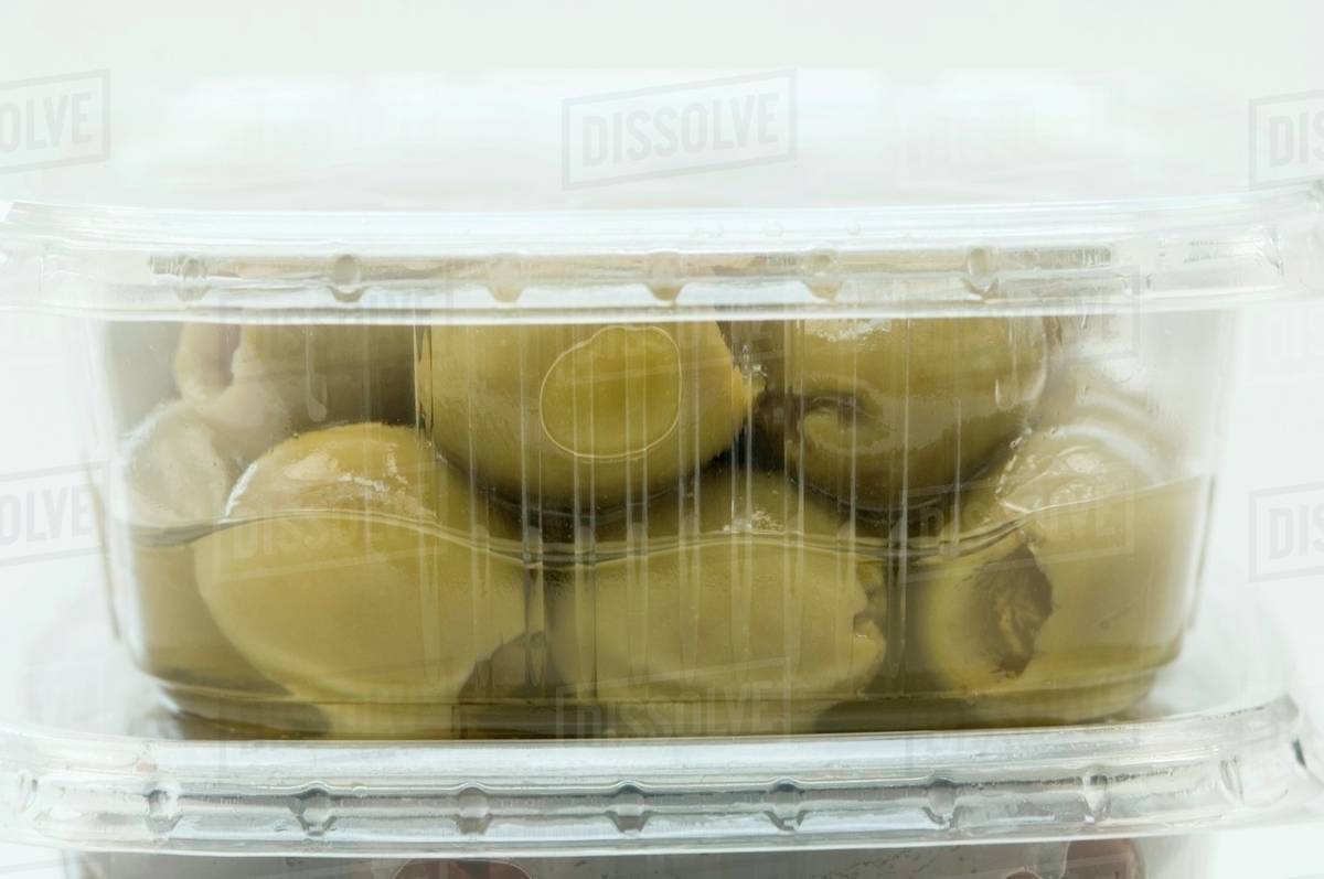Green olives in a plastic container (closeup) Stock Photo Dissolve