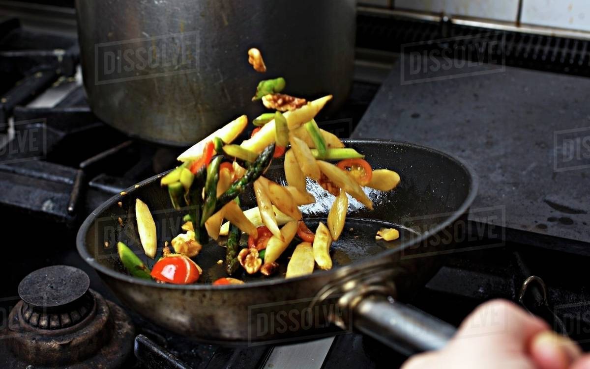 Vegetables being sauteed in a pan on a hob Stock Photo Dissolve