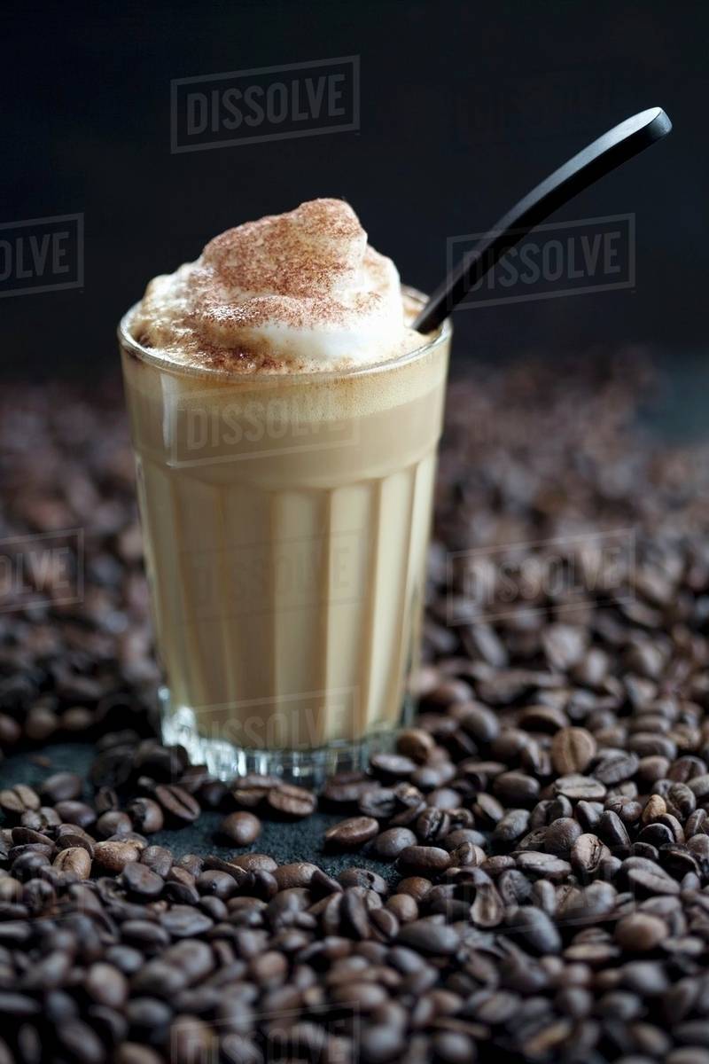 A glass of latte macchiato on coffee beans Stock Photo Dissolve