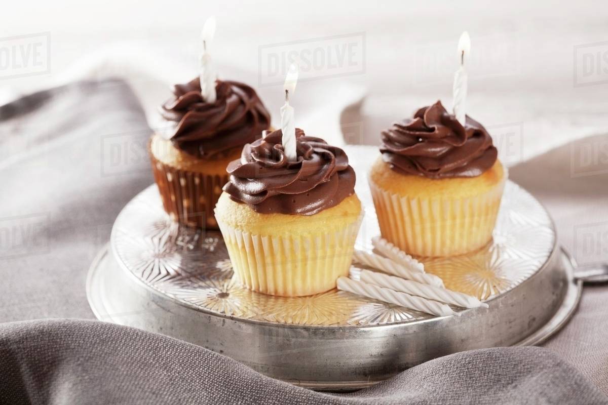 Three Birthday Cupcakes With Lighted Candles Stock Photo Dissolve