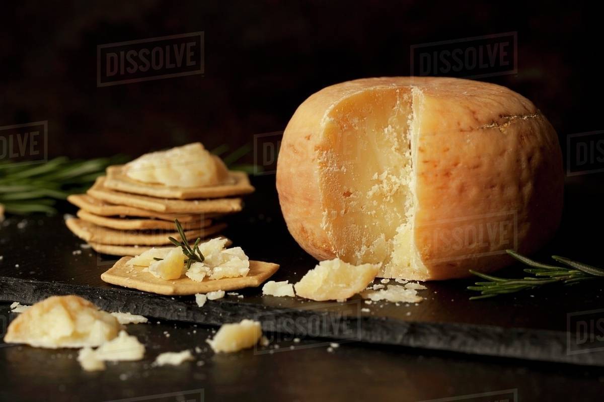 A wheel of Pecorino cheese with crackers and rosemary Stock Photo