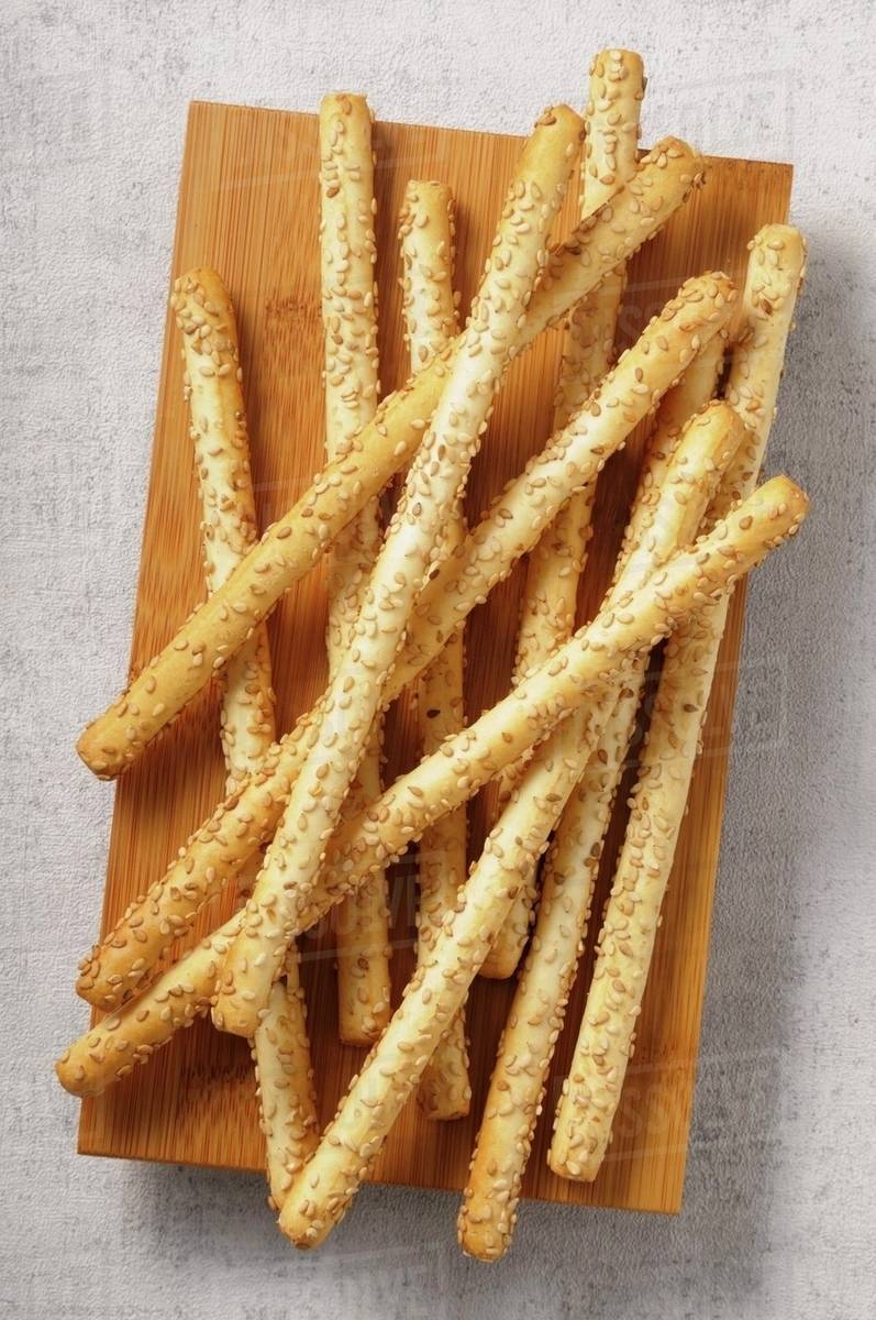 Sesame seed grissini on a wooden board Stock Photo Dissolve