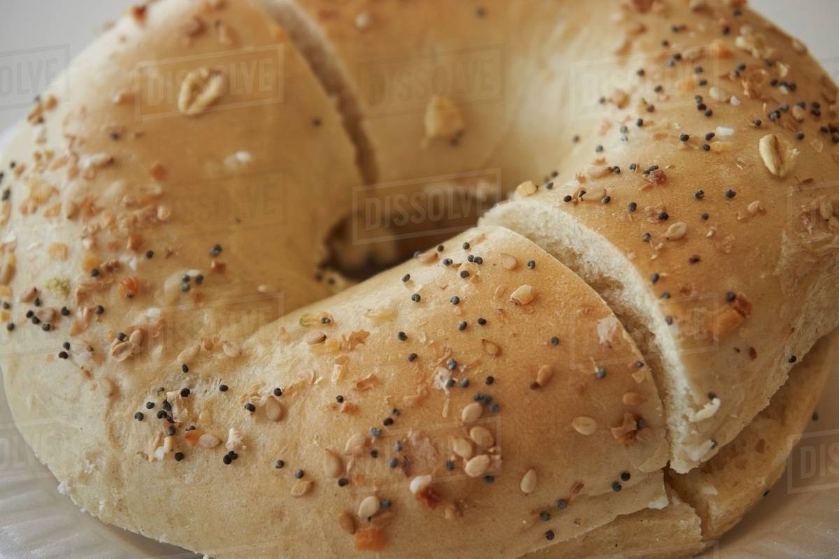 A sesame and poppy seed bagel with butter, sliced Stock Photo Dissolve