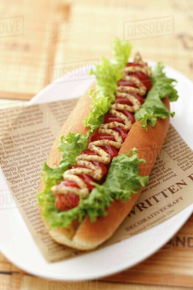 Hot dog with ketchup and lettuce on newspaper Stock Photo Dissolve