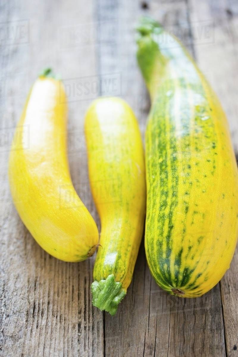 Yellow courgettes on a wooden surface Stock Photo Dissolve