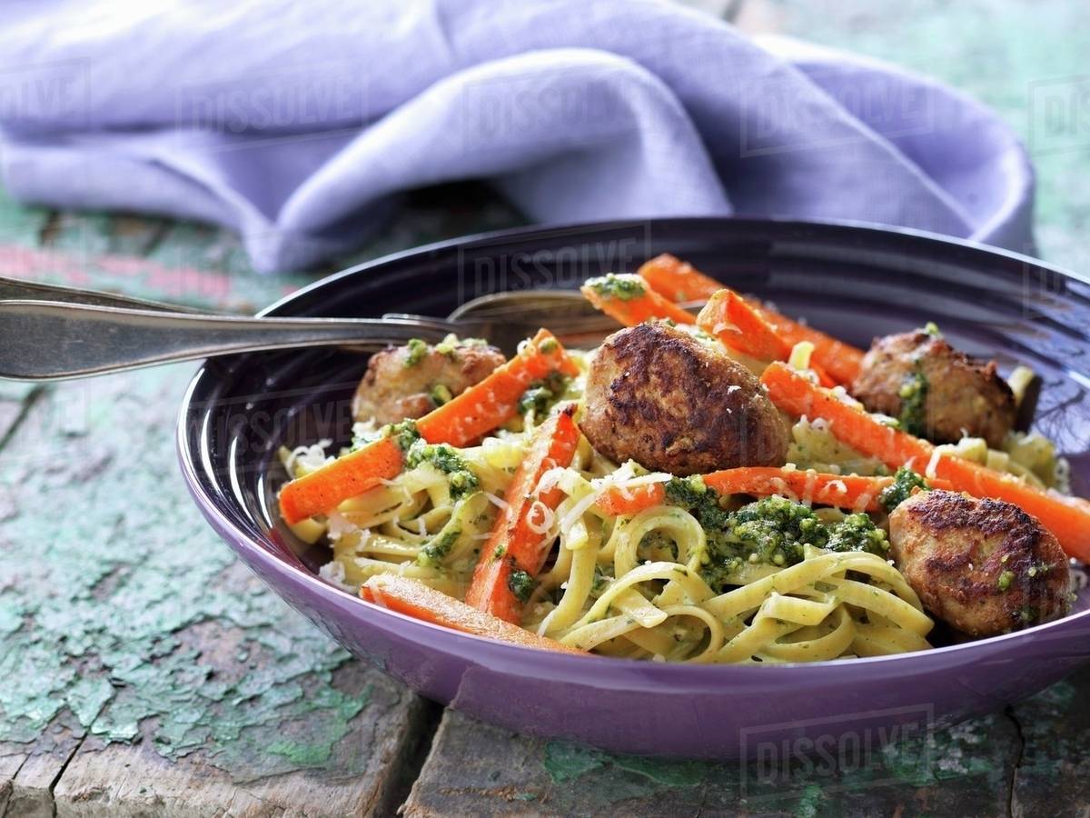 Veal meatballs in a green pesto sauce with noodles Stock Photo Dissolve