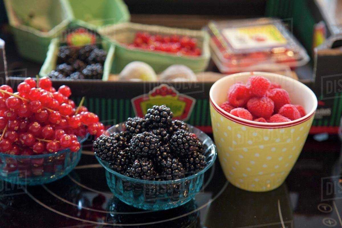 Assorted berries in bowls and packaged in a crate Stock Photo Dissolve