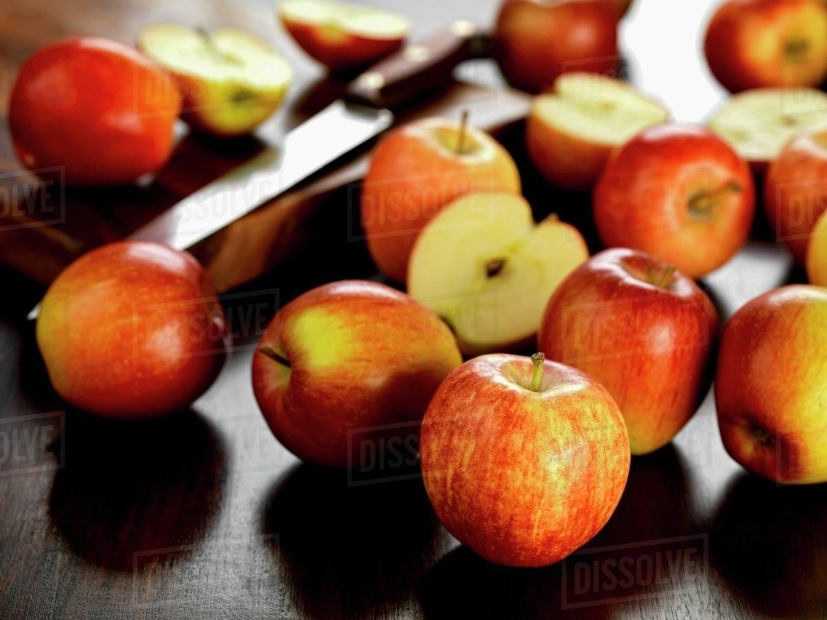Several Braeburn apples, whole and halved Stock Photo Dissolve