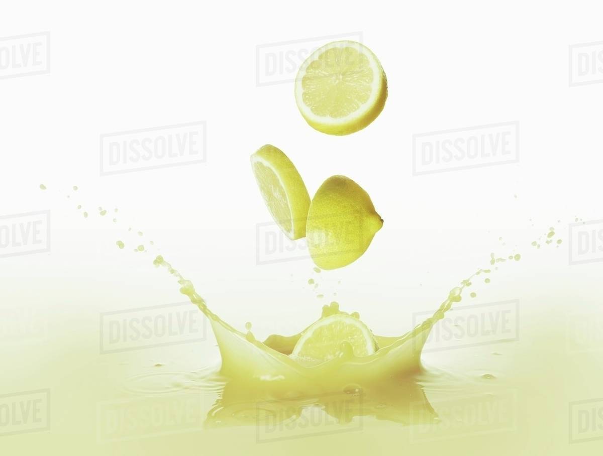 Lemons falling into lemon juice Stock Photo Dissolve