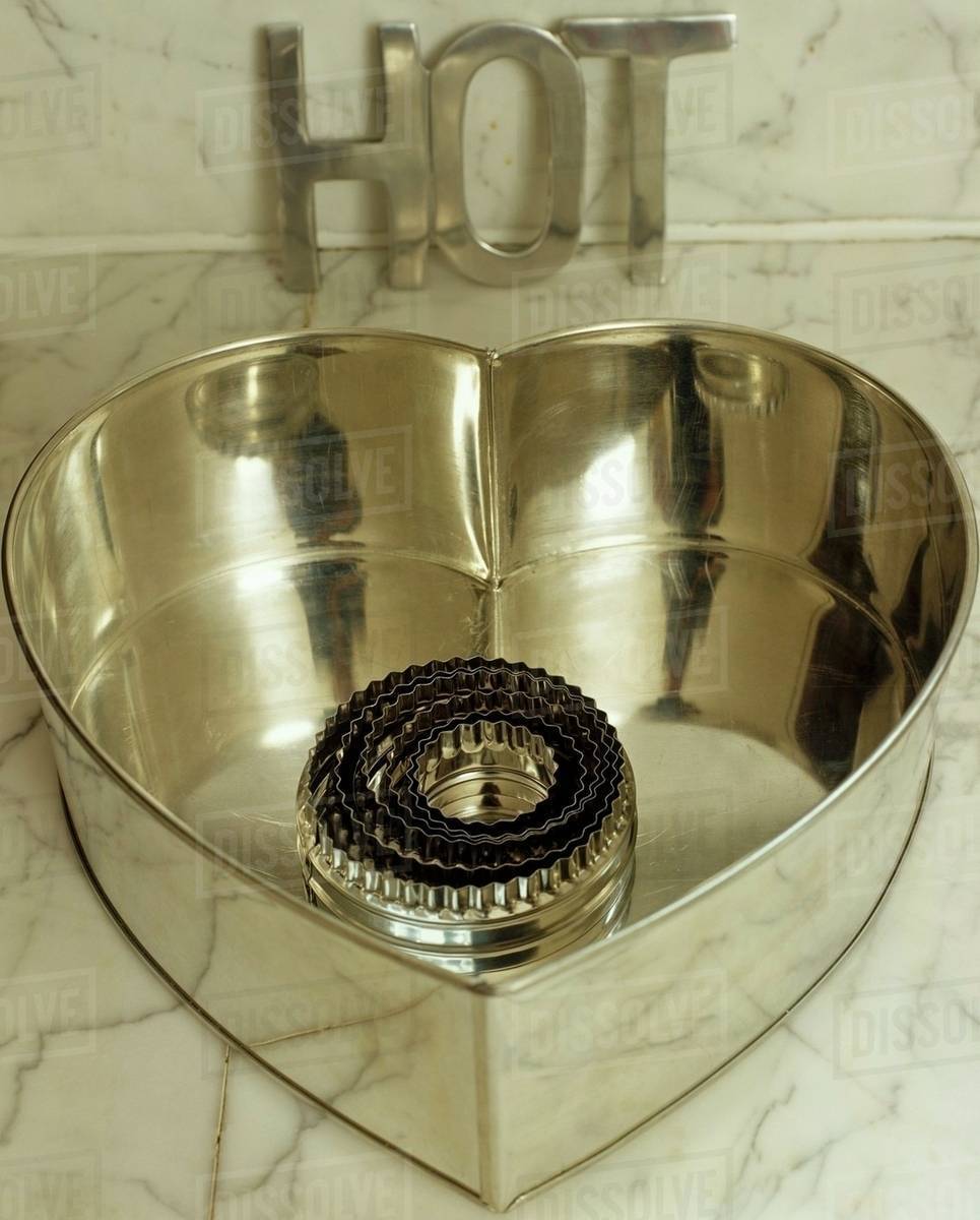 Close up of metal cake tin and biscuit cutters on marble worktop