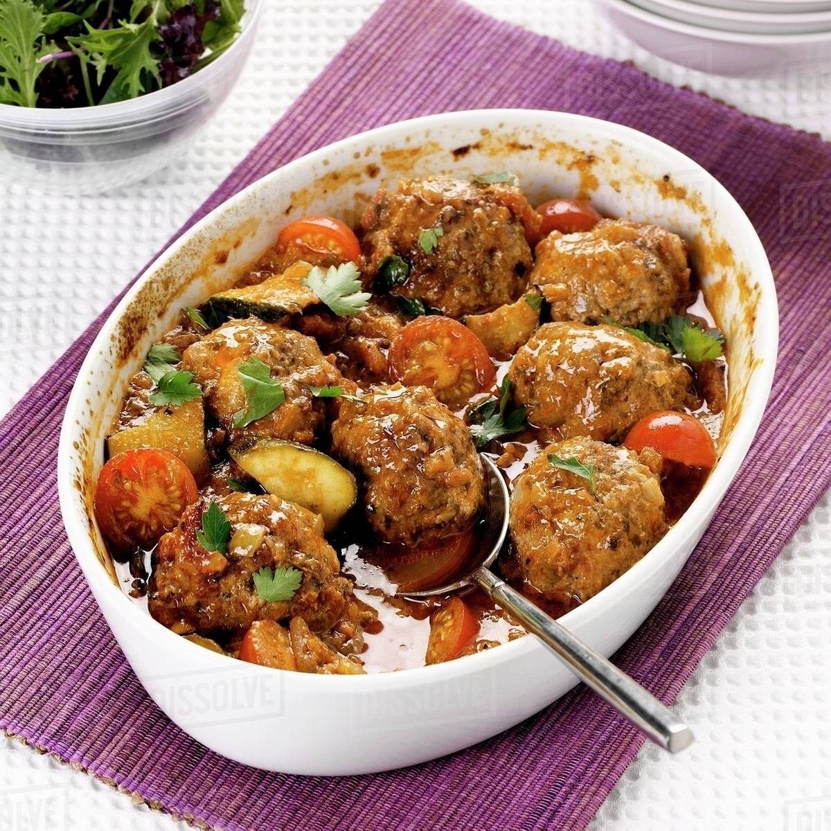 Oven-baked lamb meatballs with tomatoes and courgettes - Stock Photo