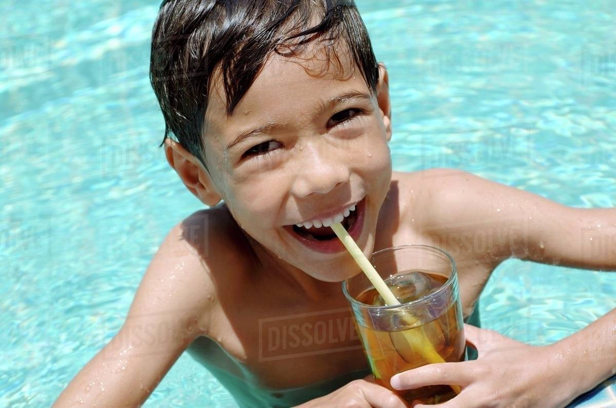 Boy drinking iced tea in pool Stock Photo Dissolve