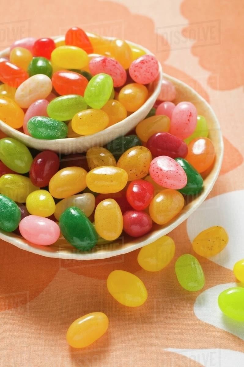 Coloured jelly beans in and beside two bowls Stock Photo Dissolve