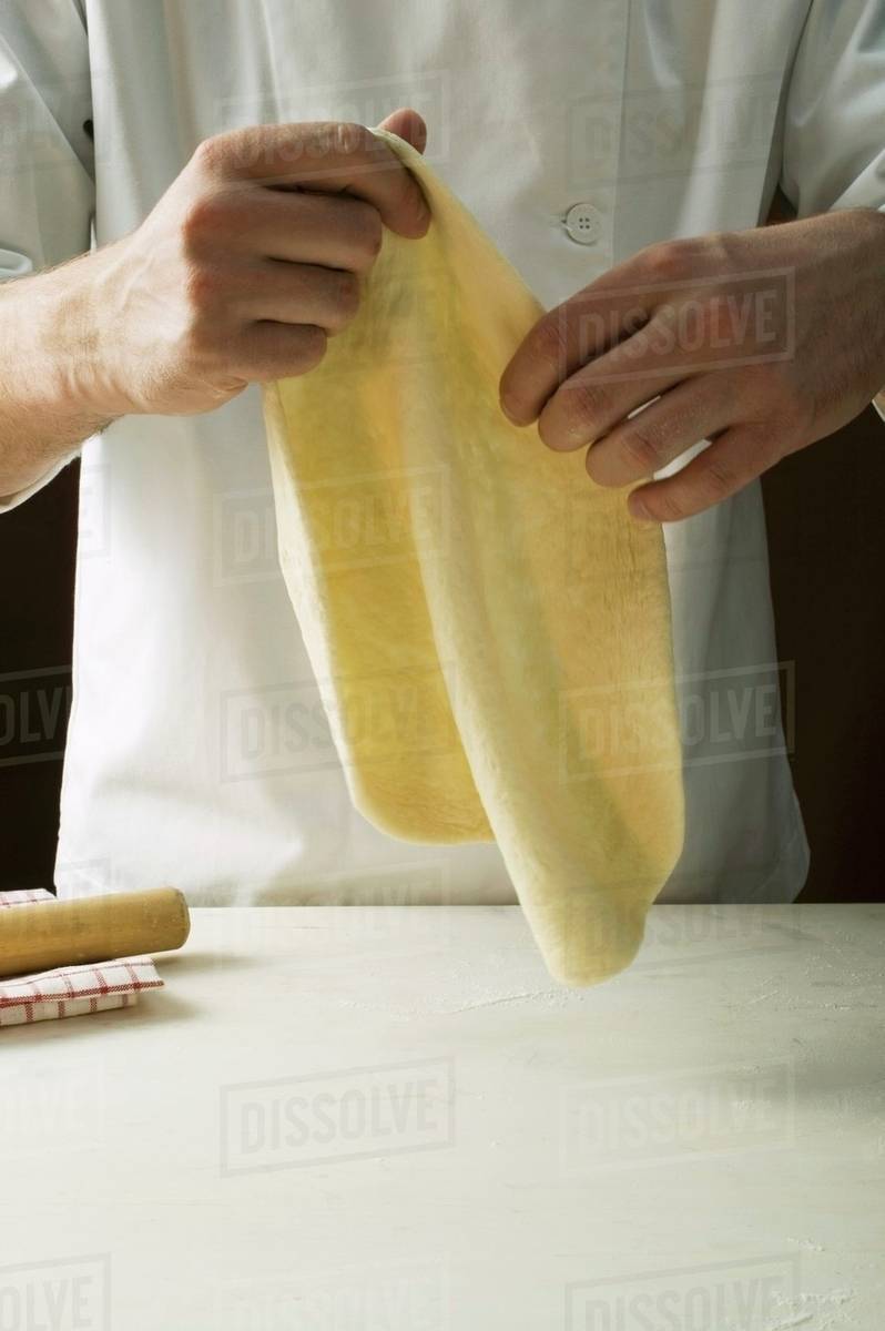 Shaping pizza dough by hand (stretching) Stock Photo Dissolve