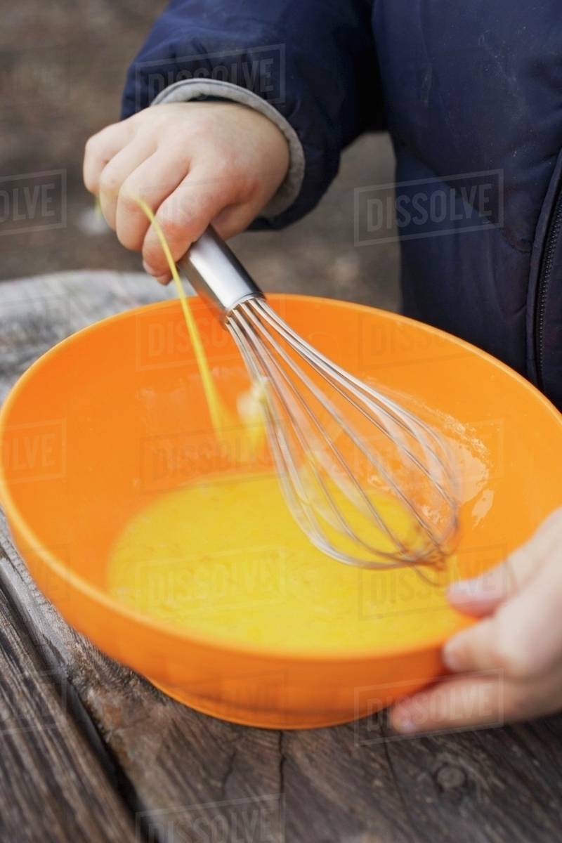 Child beating egg yolks with whisk Stock Photo Dissolve