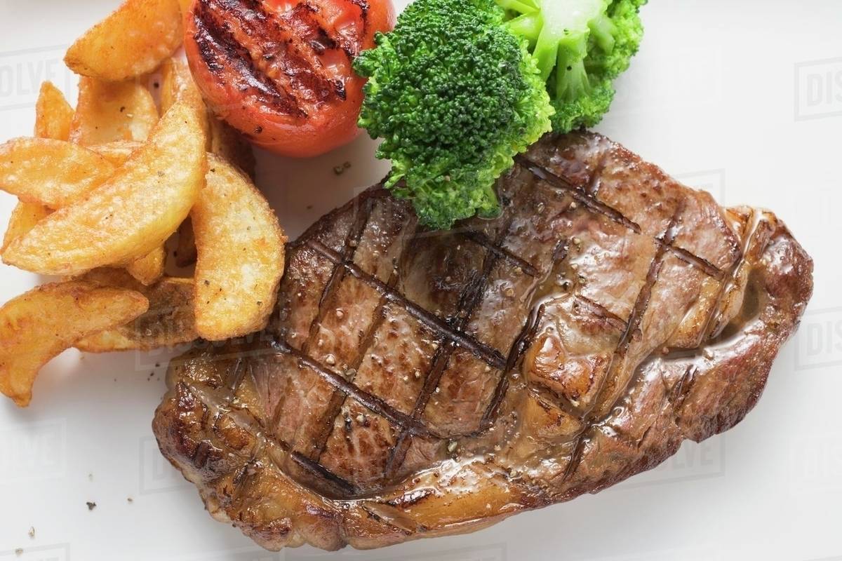 Grilled beef steak with vegetables and potato wedges Stock Photo