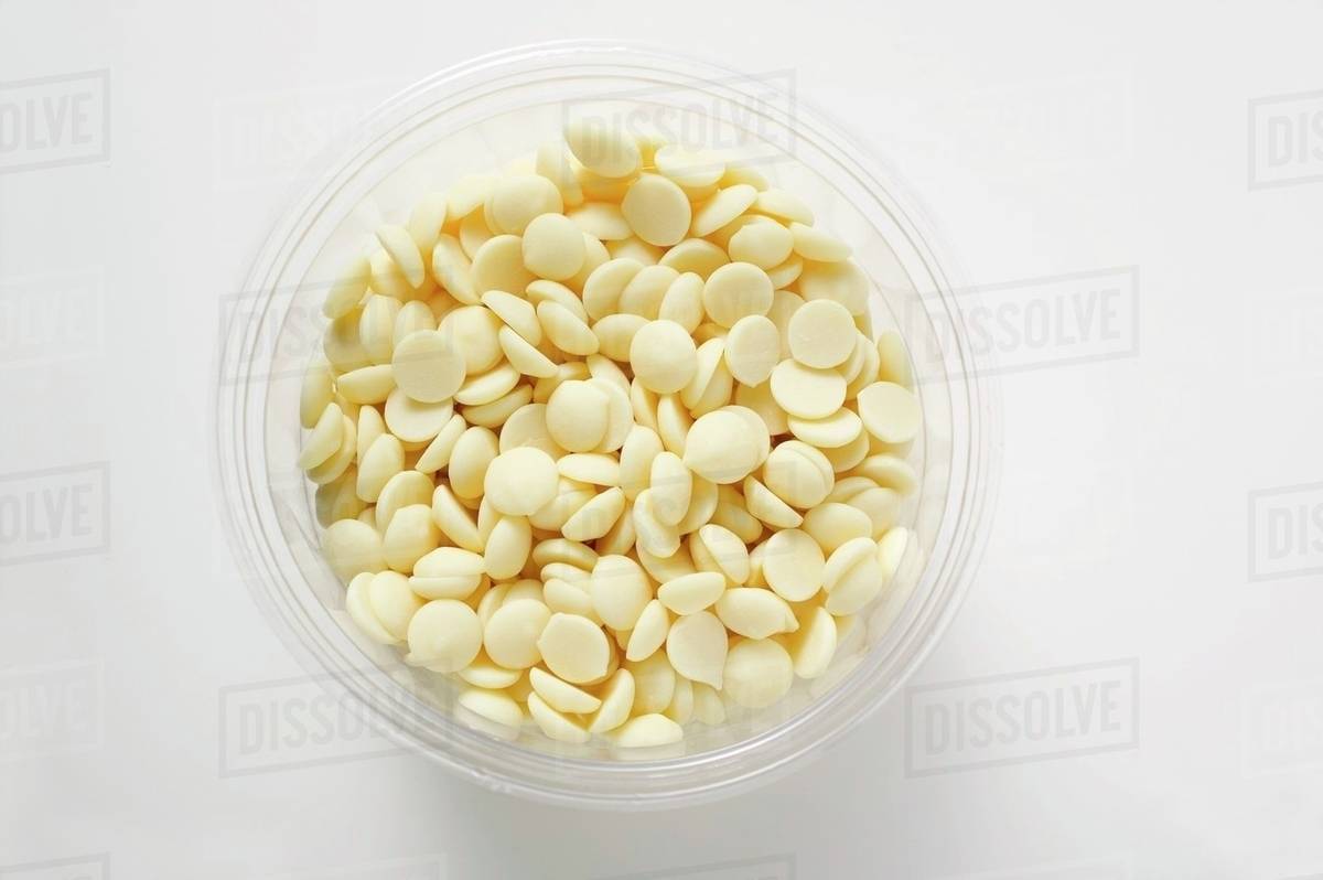 White chocolate chips in plastic tub (overhead view) Stock Photo Dissolve