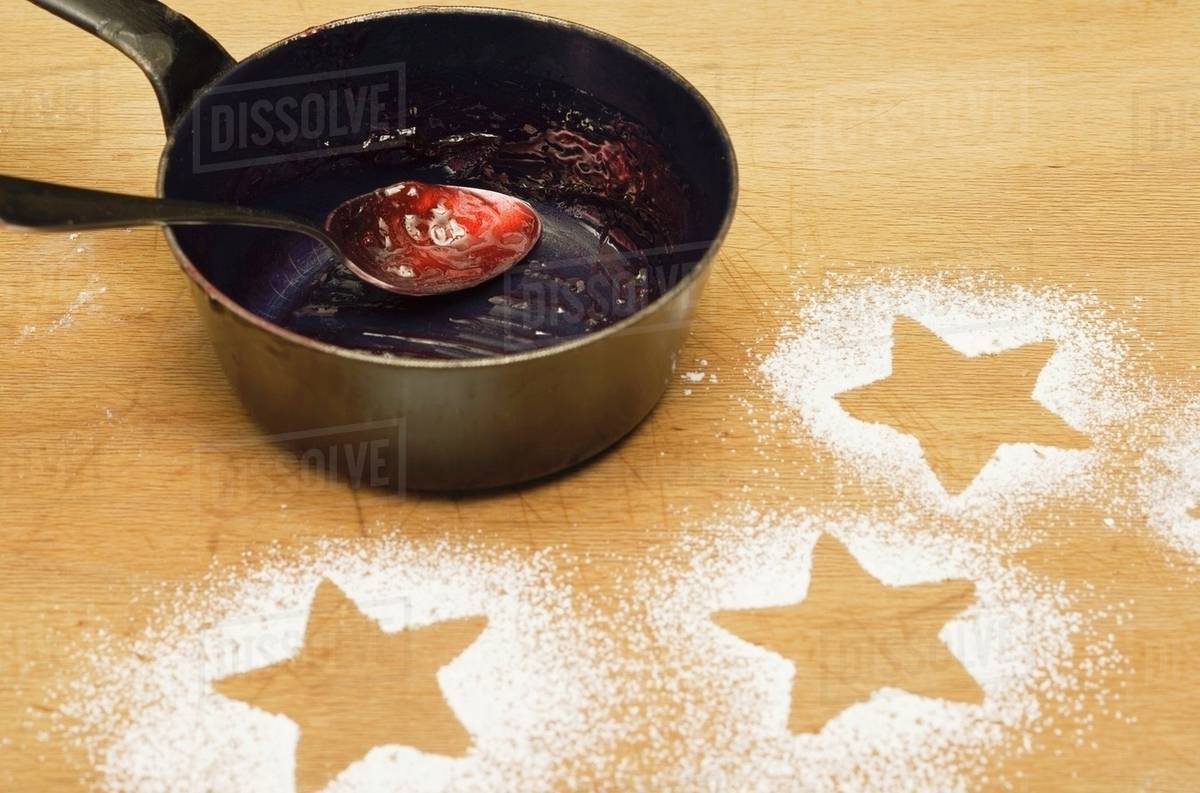 Star shapes outlined in icing sugar and saucepan with jam Stock Photo