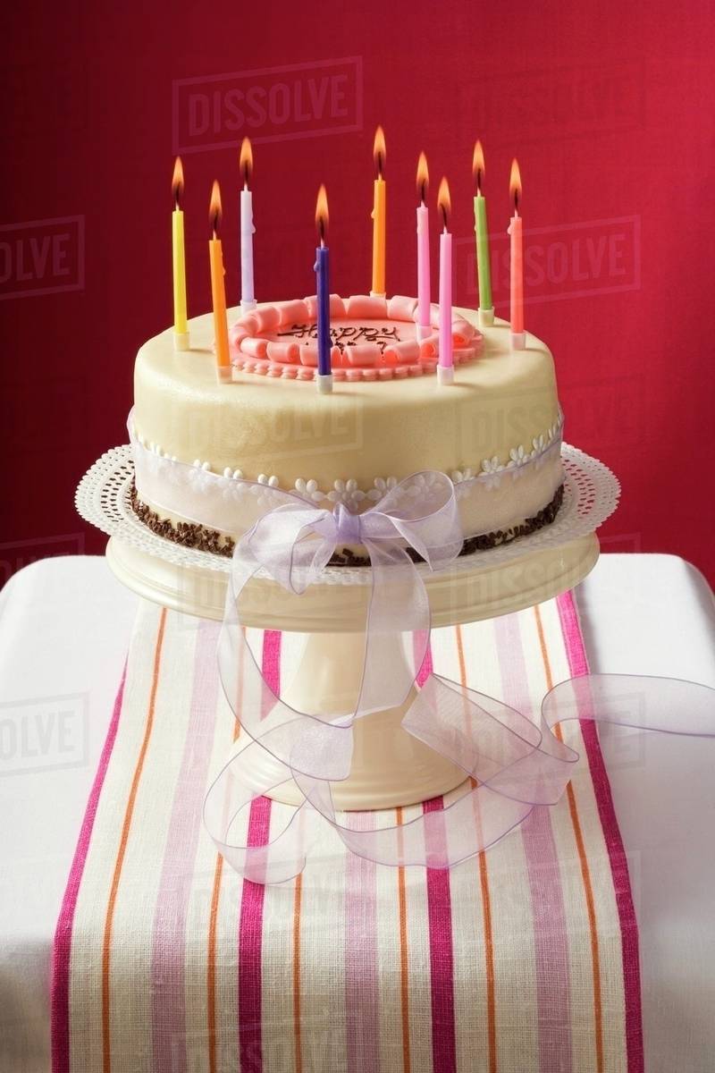 Birthday cake with burning candles on cake stand Stock Photo Dissolve
