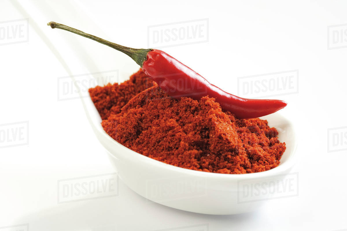 Ground cayenne pepper and red chilli pod Stock Photo Dissolve