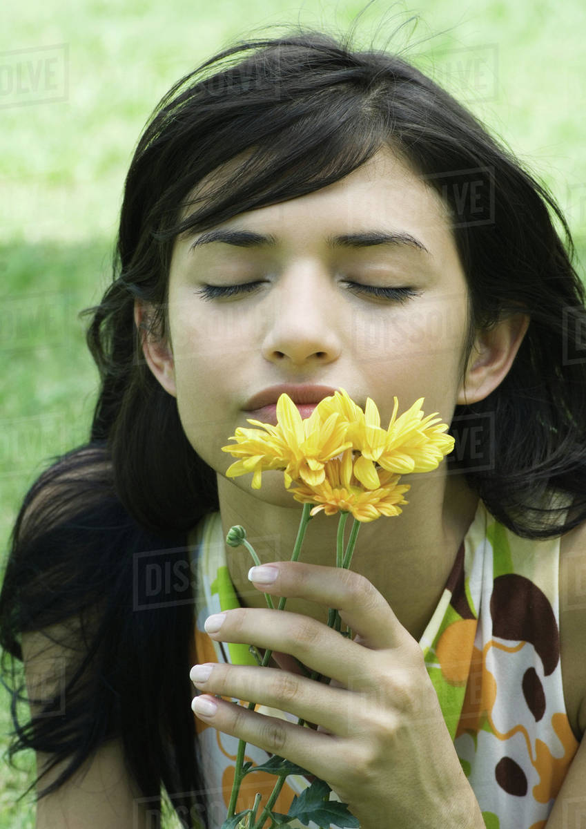 Woman smelling flowers, eyes closed Stock Photo Dissolve
