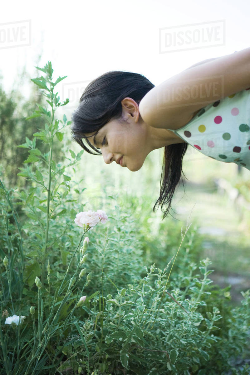 Young woman bending over to smell flowers in garden Stock Photo