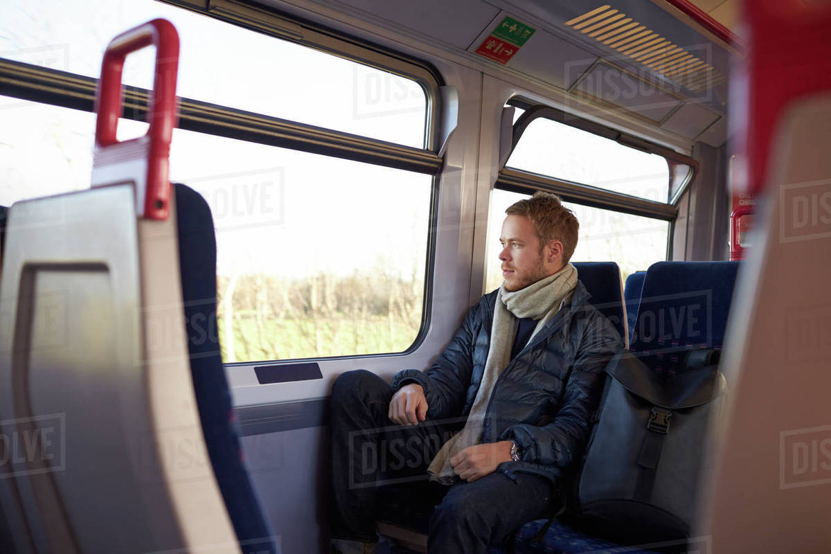 Young man sitting in train carriage on railway journey Stock Photo