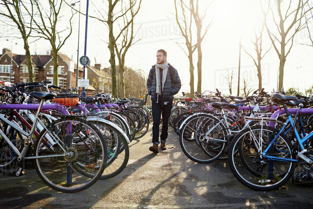 Man leaving bike in cycle park at railway station Stock Photo Dissolve