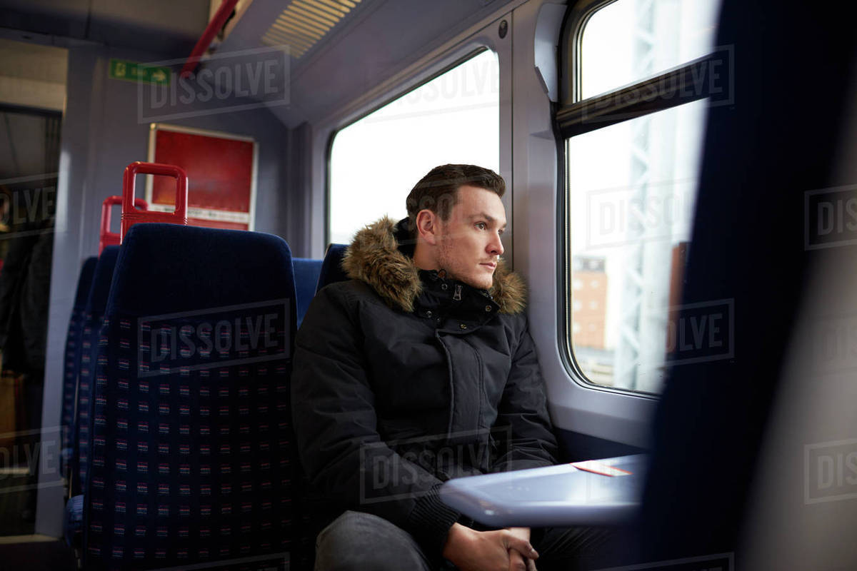 Young man sitting in train carriage on railway journey Stock Photo