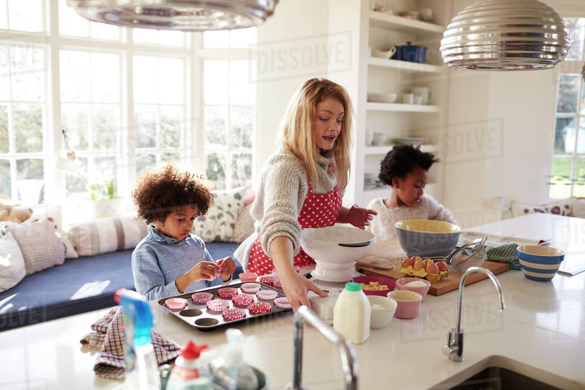 Mother baking cake with children in kitchen at home Stock Photo