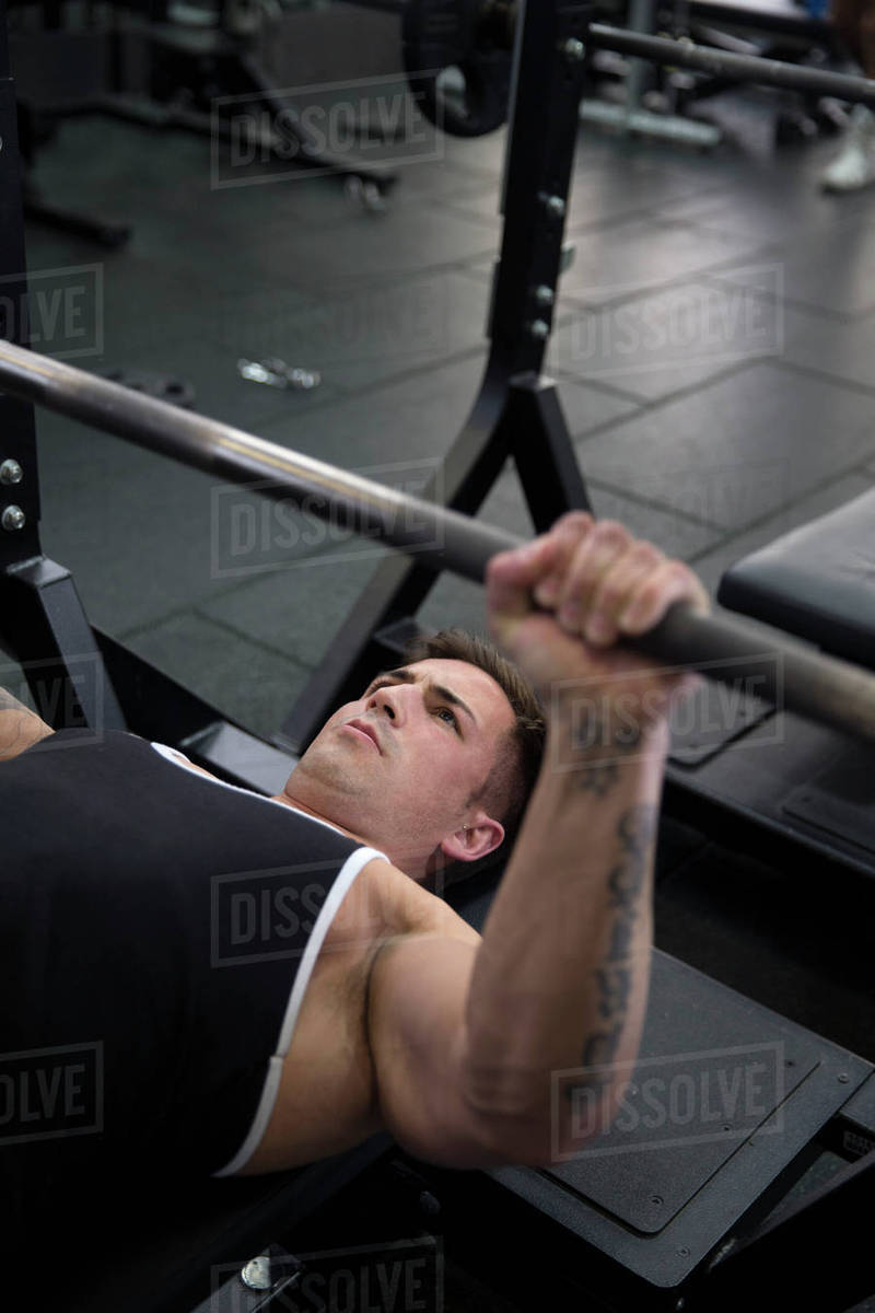 Young man bench pressing weights in gym Stock Photo Dissolve