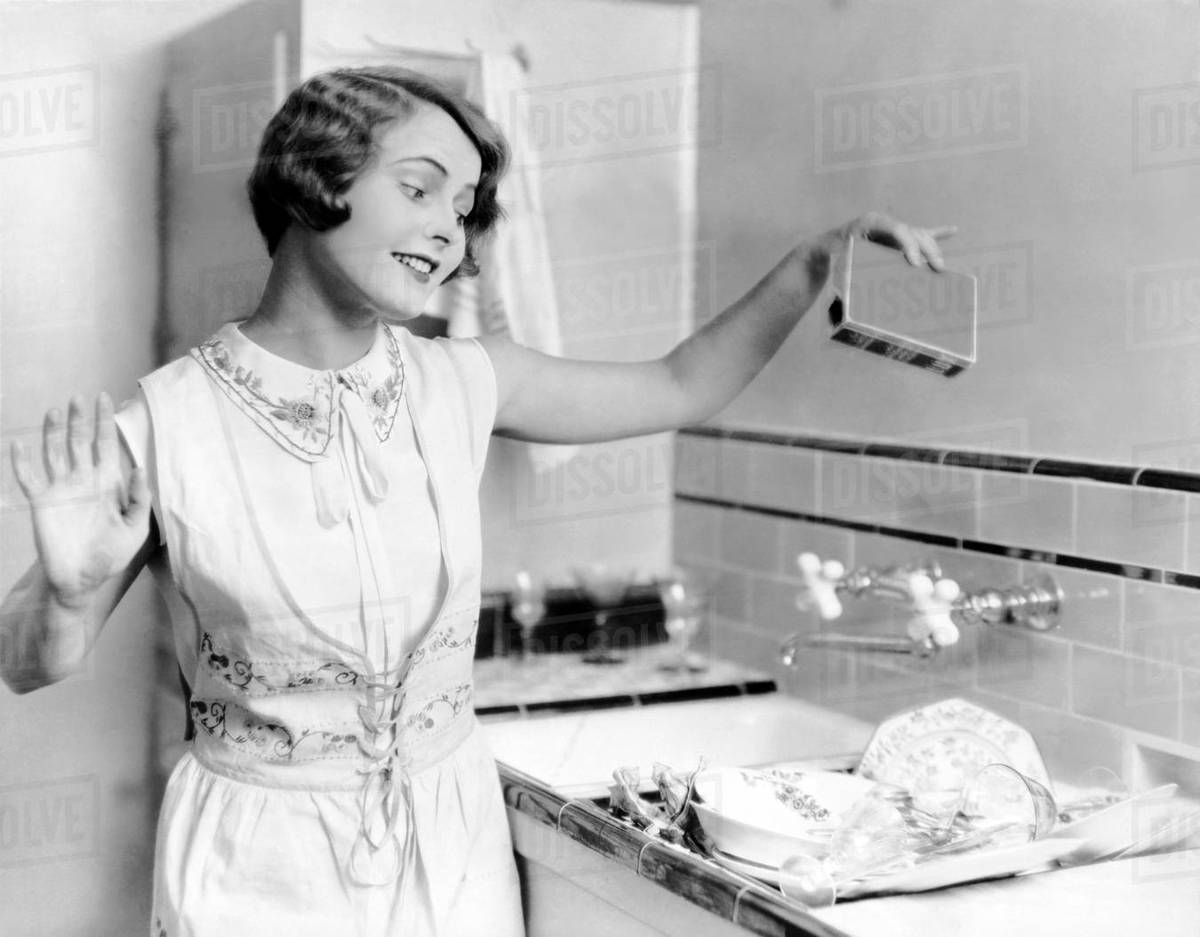 Woman pouring soap on dishes Stock Photo Dissolve