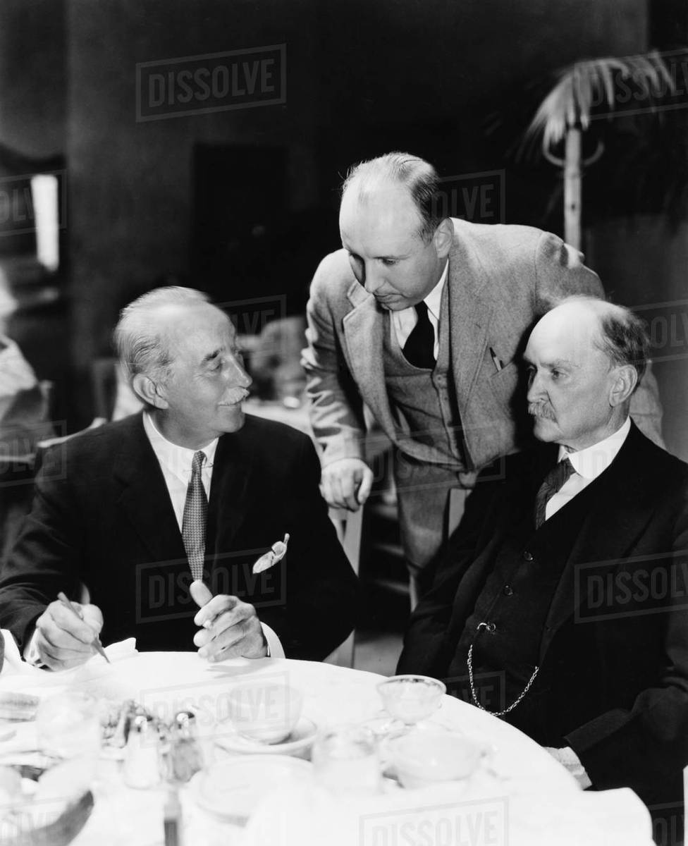 Three men sitting together at a table - Royalty-free Stock Photo | Dissolve
