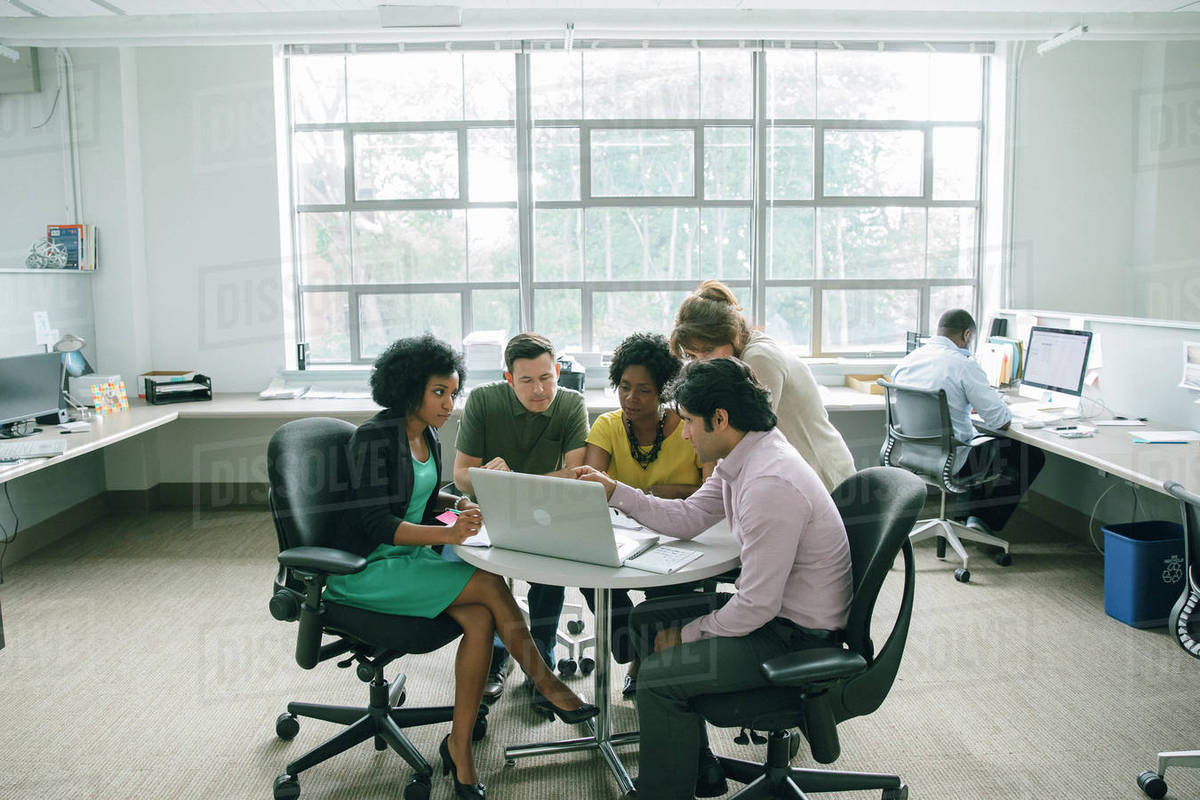 Business people holding a meeting at a round table in an office Stock Photo Dissolve