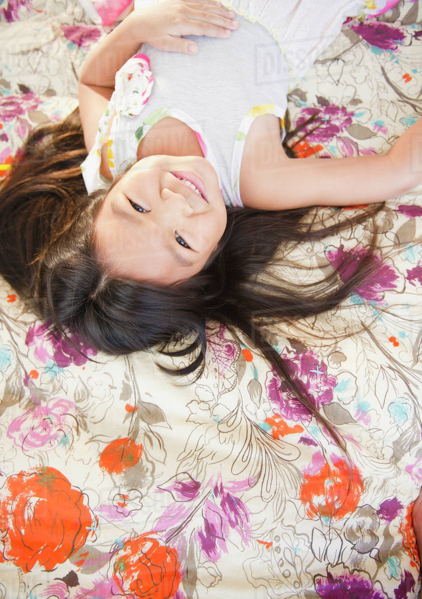 Smiling Korean girl laying on bed Stock Photo Dissolve