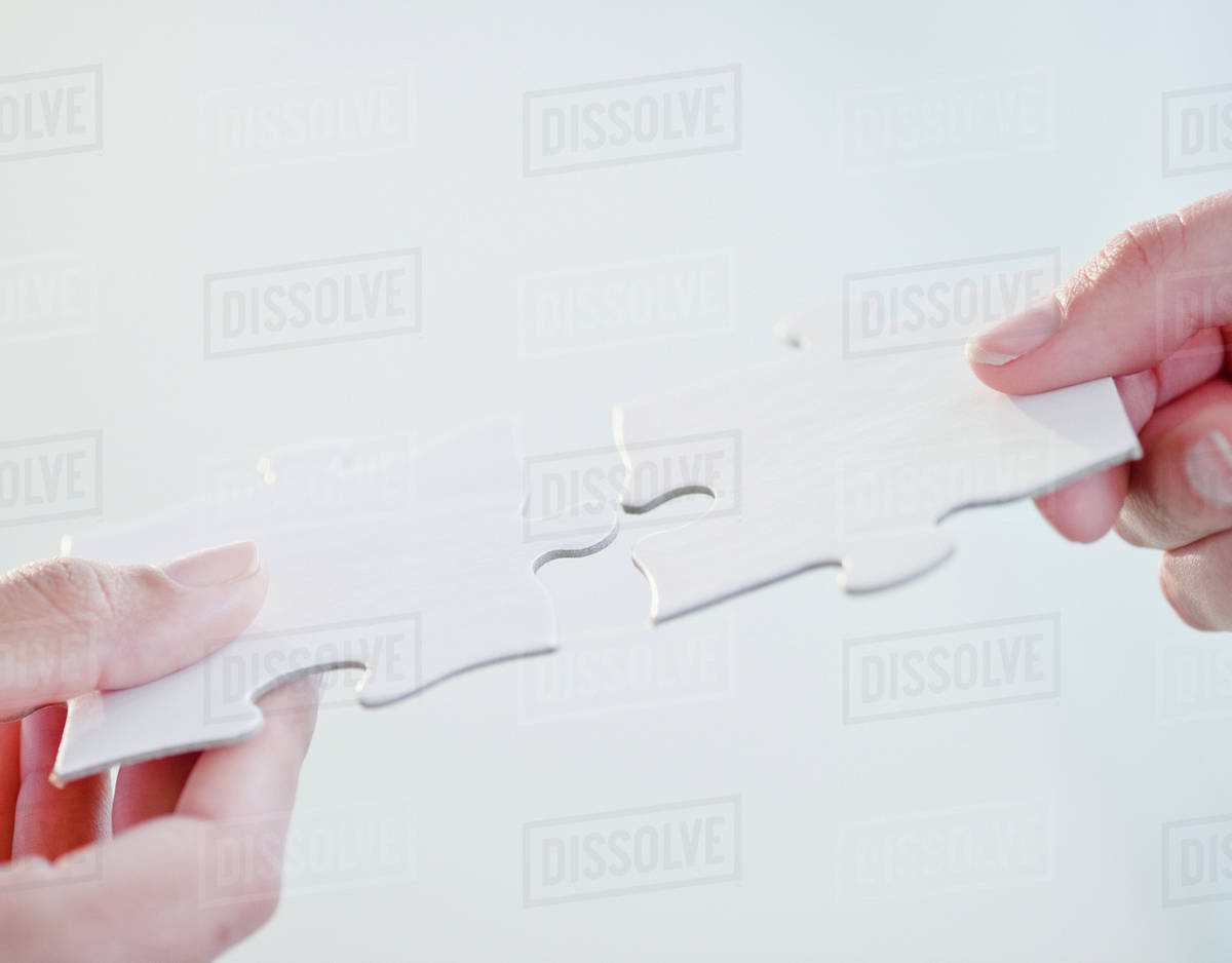 hands connecting jigsaw puzzle pieces stock photo dissolve