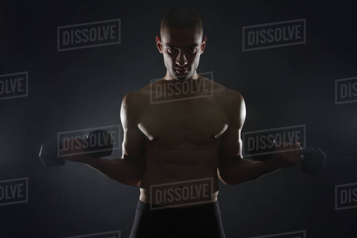 Mixed race athlete weight training with dumbbells Stock Photo Dissolve