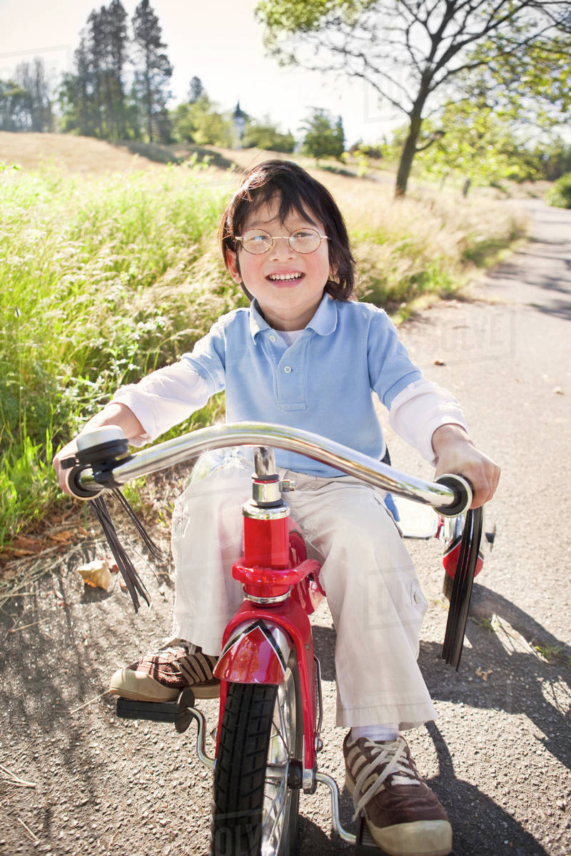 Boy riding tricycle on sidewalk Stock Photo Dissolve