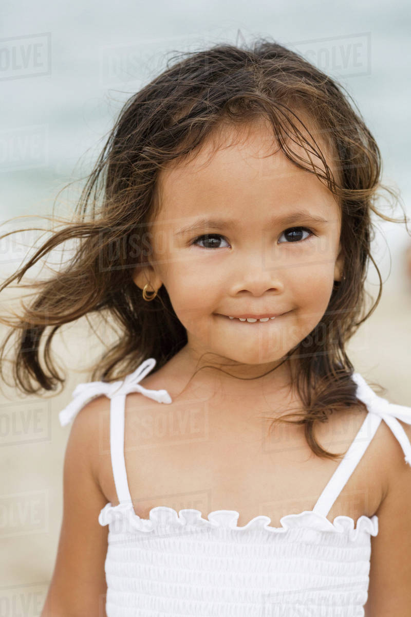 Mixed race girl smiling on beach Stock Photo Dissolve