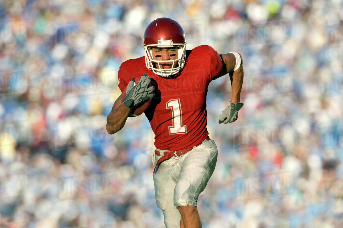 African American football player running on field in game Stock Photo