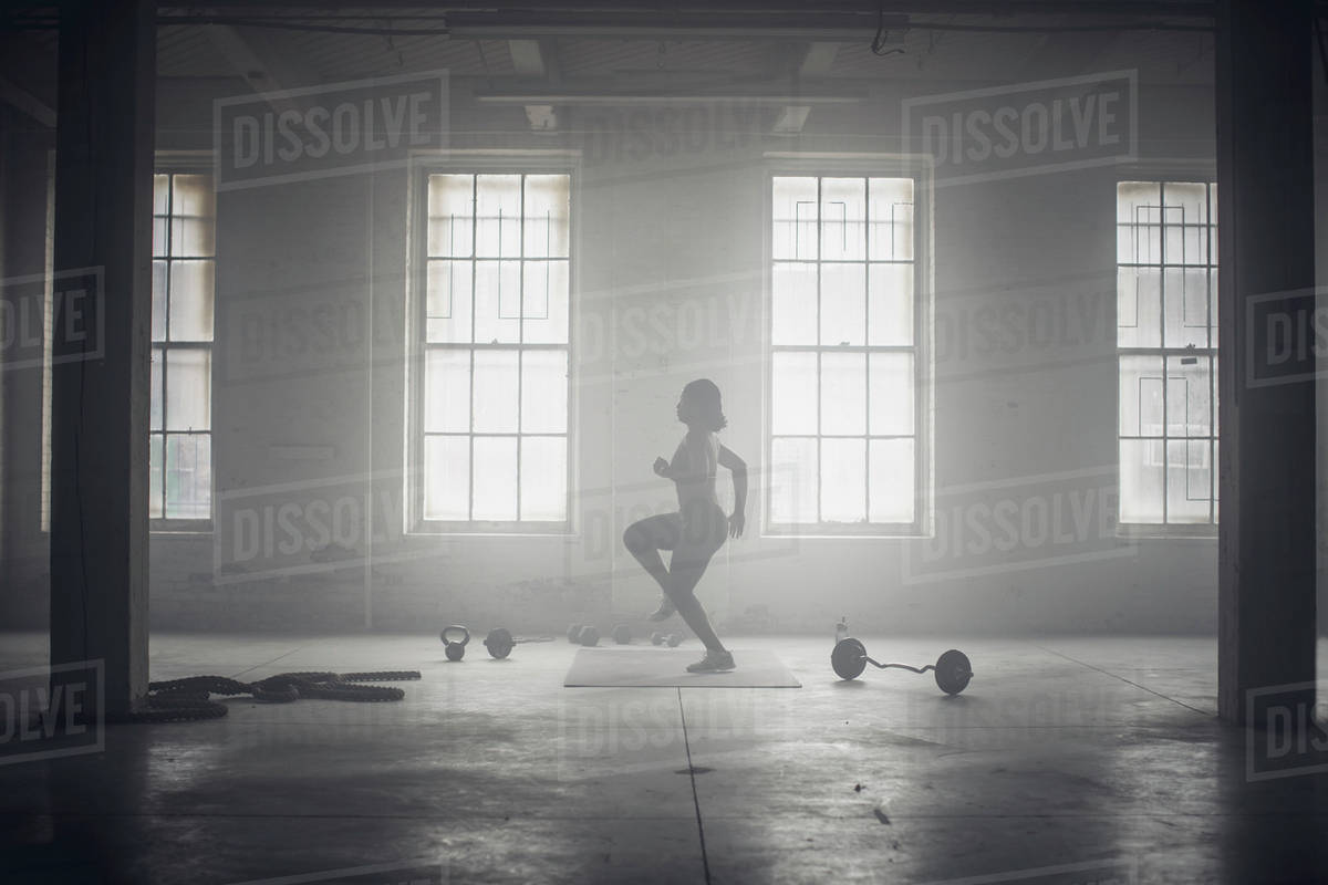 Black woman exercising in dark gym - Royalty-free Stock Photo | Dissolve