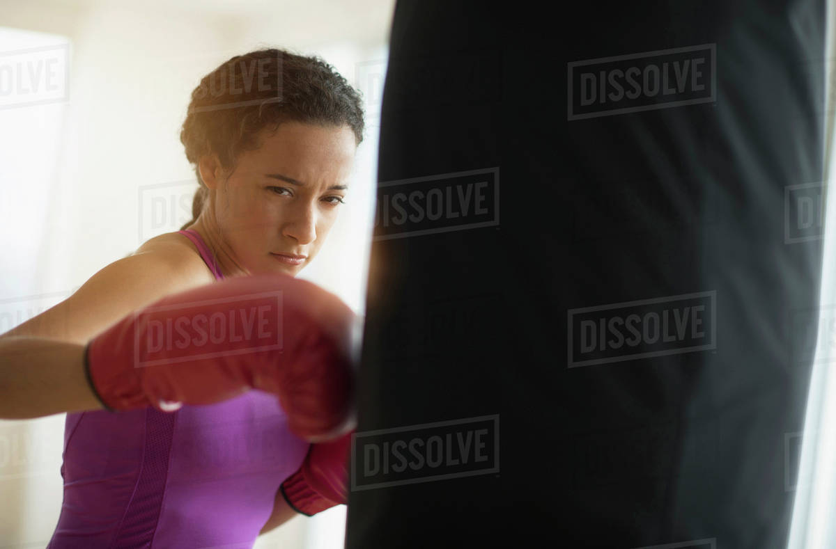 Mixed race woman hitting punching bag in gym Royalty-free stock photo